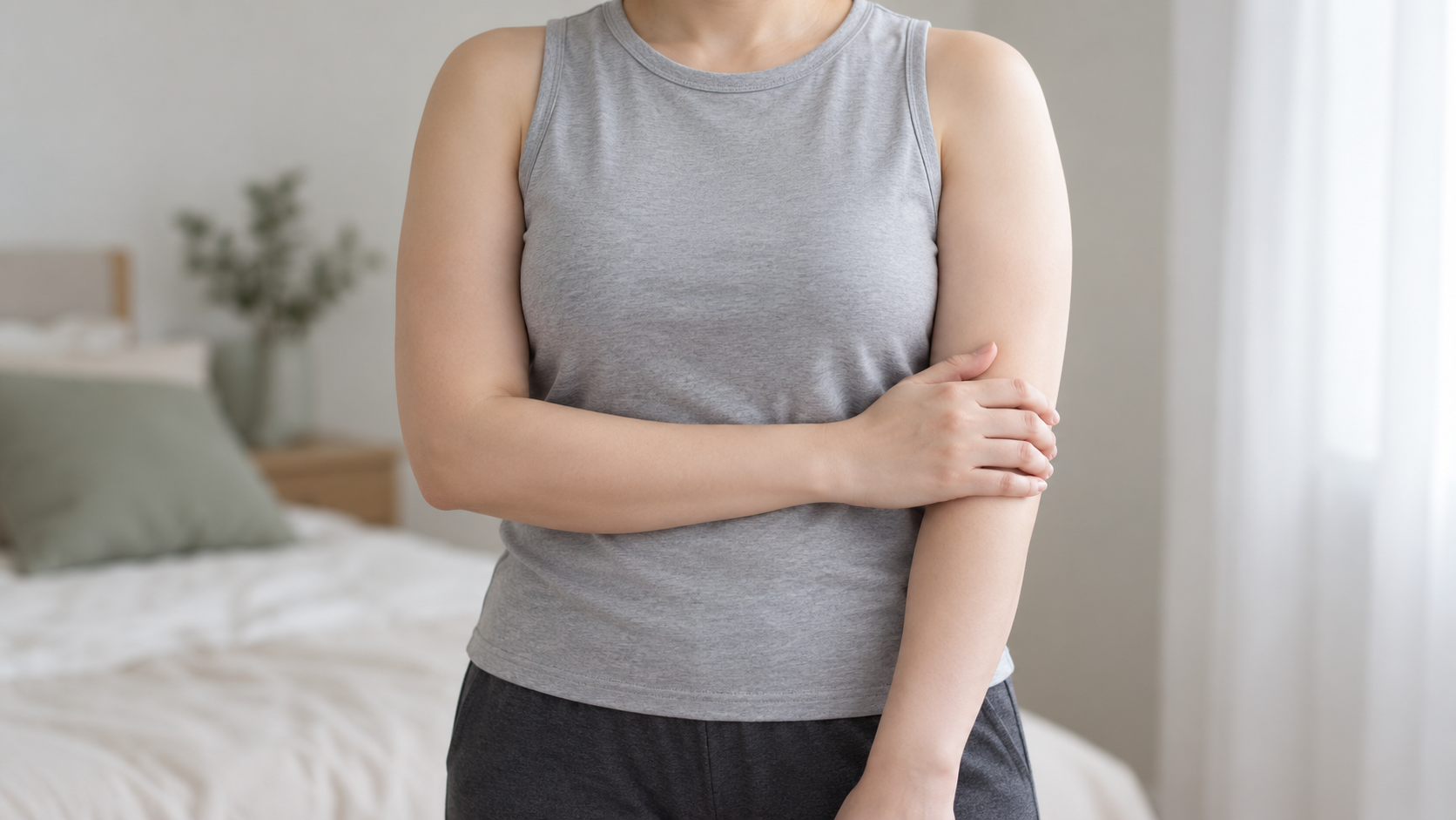 얼굴이 보이지 않는, 회색 민소매 옷을 입고 팔 상태를 살피는 여성의 연출 이미지